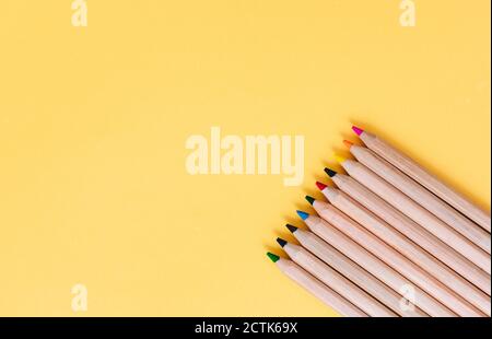 Colored pencils arranged on yellow background Stock Photo