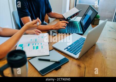 Computer programmers discussing over laptop at office desk Stock Photo
