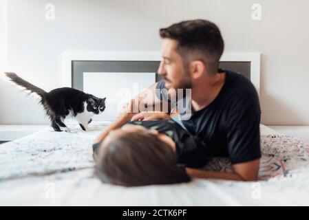 Couple lying down on bed while playing with cat at home Stock Photo