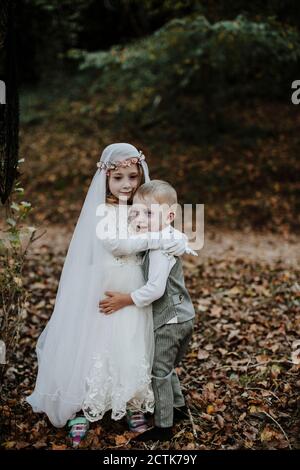 Sister embracing brother at halloween party while standing in forest Stock Photo