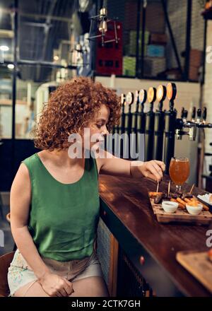 Woman having tapas at the counter in a pub Stock Photo