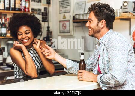 Man touching cheerful female bartender while flirting with her at bar counter Stock Photo