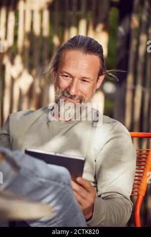 Close-up of bearded man reading book while relaxing on chair in yard Stock Photo