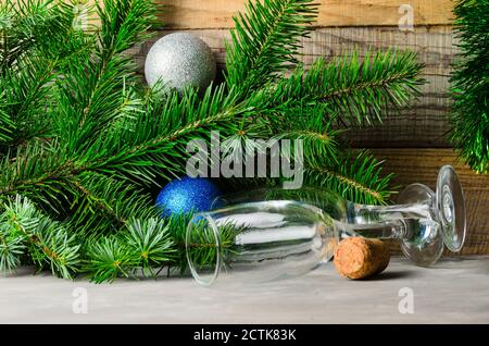 Spruce branches with green needles and Christmas balls on a wooden background. Two empty glasses. Selective focus. Stock Photo