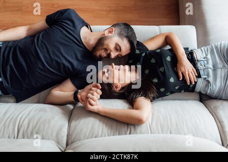 Couple relaxing while lying down on sofa at home Stock Photo