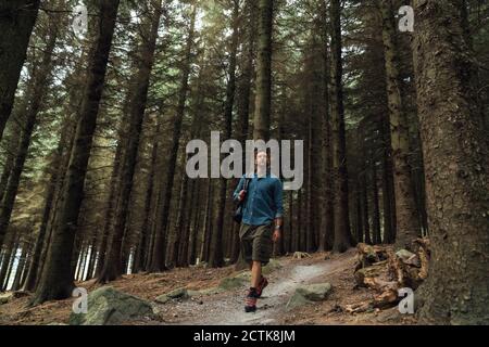 Male hiker walking on trail amidst trees in woodland Stock Photo