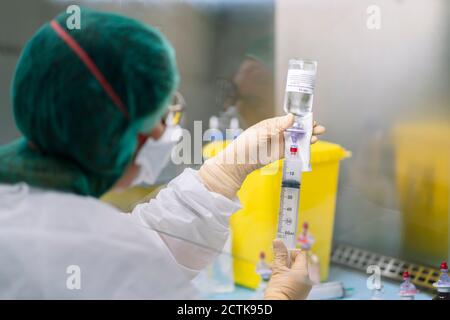 Close-up of female pharmacist injecting liquid in bottle at laboratory Stock Photo