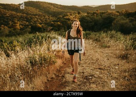 Adventurous woman walking in forest during sunset Stock Photo