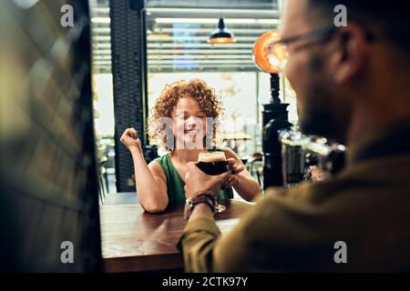 Barkeeper handing over glass of beer to woman in a pub Stock Photo