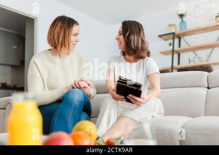 Smiling friends talking while using digital tablet at home Stock Photo