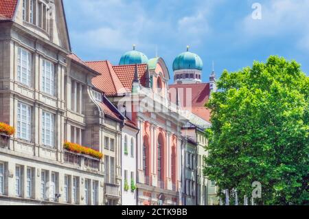 Germany, Bavaria, Munich, Row of old townhouses with domes of Frauenkirche in background Stock Photo