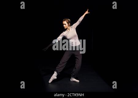 Female ballet dancer rehearsing on black stage Stock Photo