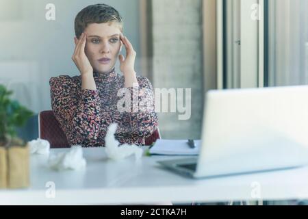 Businesswoman at desk in office having headaches Stock Photo