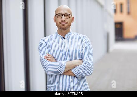 Serious man standing with arms crossed on street Stock Photo