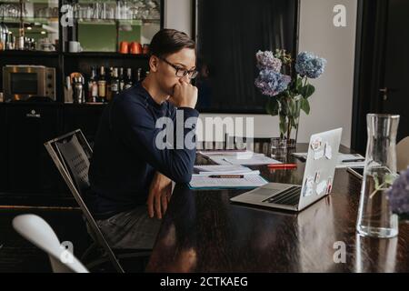 Young man studying from home, using laptop Stock Photo