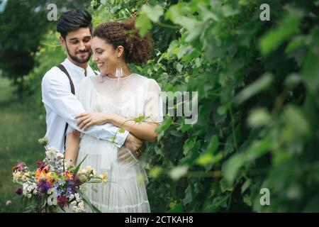 Groom embracing bride while standing at garden Stock Photo