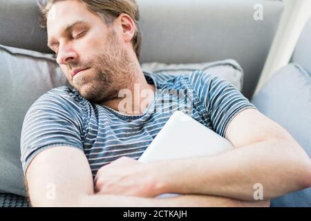 Man with laptop sleeping on sofa at home Stock Photo