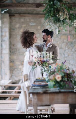 Bride and groom looking at each other while standing by wedding table Stock Photo