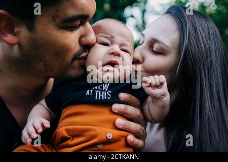 Young parents kissing cute baby boy Stock Photo