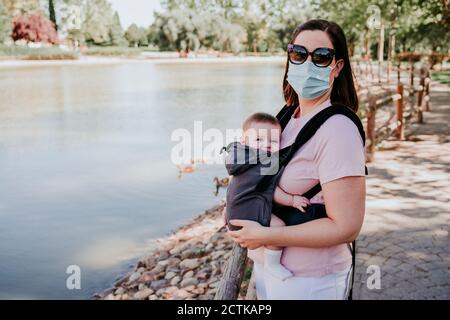 Mother and baby girl in baby carrier in park Stock Photo