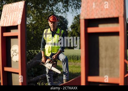Man holding chainsaw while standing in forest Stock Photo