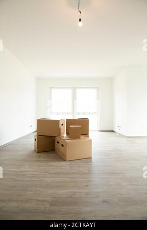 Light bulb hanging over cardboard boxes on hardwood floor in new house Stock Photo