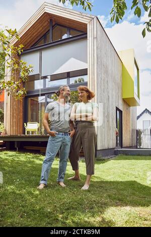 Mature man with hands in pockets looking at woman while standing outside tiny house Stock Photo