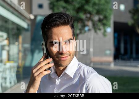 Close-up of confident businessman looking away while talking over smart phone Stock Photo