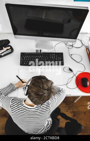 Boy doing homework on desk Stock Photo