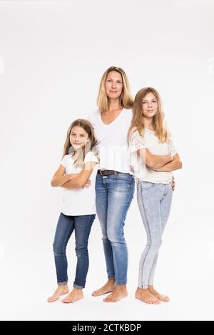Mother with daughters standing against white background Stock Photo