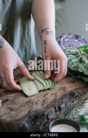 Young woman preparing cucumber on cutting board Stock Photo