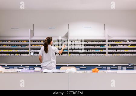 Female pharmacist arranging medicines on shelves in hospital Stock Photo