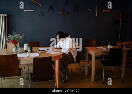 Female owner analyzing financial bills on table while sitting in coffee shop Stock Photo
