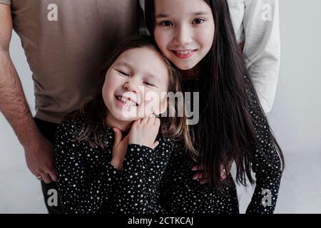 Smiling daughters standing with parents in studio Stock Photo