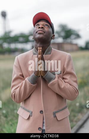 Young man praying with religious faith while standing outdoors Stock Photo