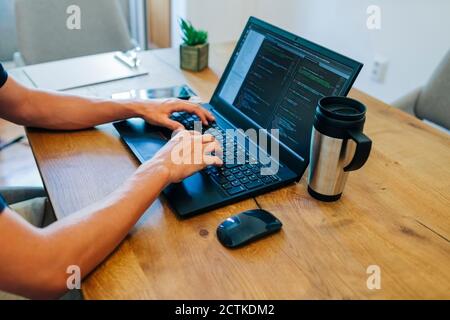 Male web designer programming through on laptop at desk in office Stock Photo