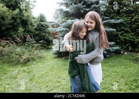 Sisters embracing each other in back yard Stock Photo