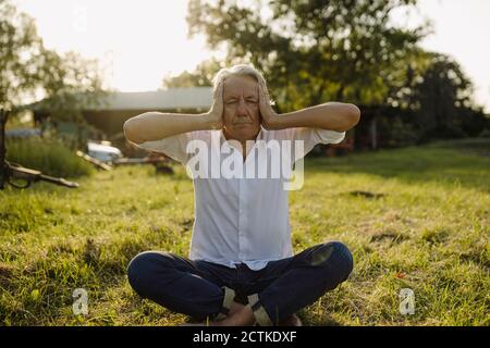 Man practicing yoga while sitting in backyard Stock Photo