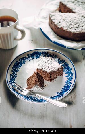 Slice of chocolate fridge tart with coconut shreds and mug of coffee Stock Photo