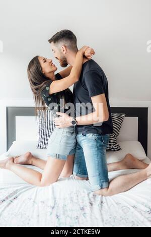 Couple embracing each other while kneeling on bed at home Stock Photo