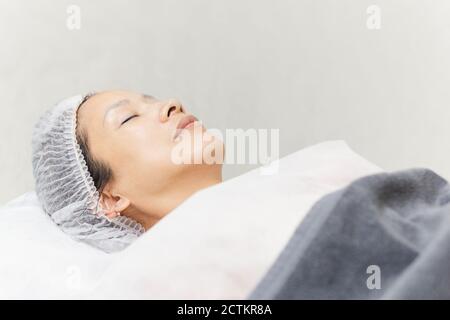 Beautiful woman with clean healthy skin relaxing lying in spa salon. Stock Photo