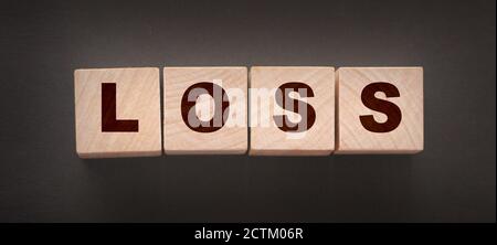 Wooden cubes with LOSS word on blacktable. Financial loss busines concept