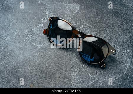 Dark male sunglasses on grey concrete surface Stock Photo by FabrikaPhoto