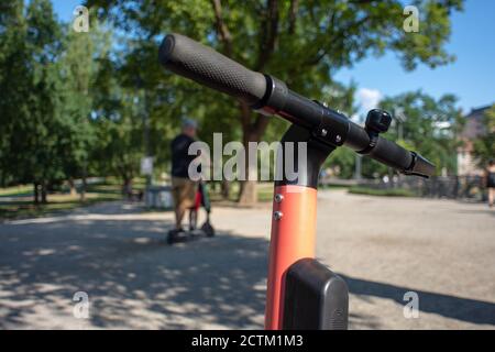 Tampere, Finland - JULY 26, 2019. A man riding an electric scooter with his son in the public park on a sunny summer day. Stock Photo