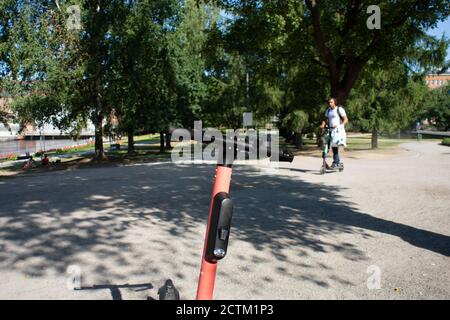 Tampere, Finland - JULY 26, 2019. An alone man riding an electric scooter in public park on a sunny summer day. Stock Photo