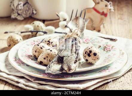 Served for Easter meal old table with plates, eggs and candles, selective focus Stock Photo