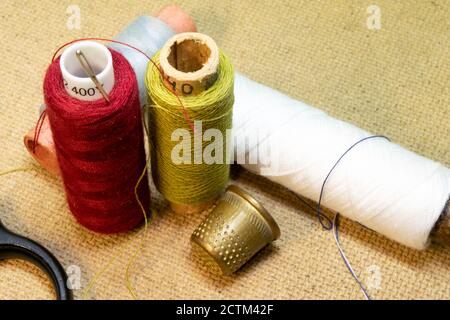 four spools of thread, needles, thimble and scissors are on the table Stock Photo