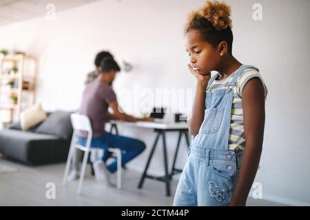 Sad little girl waiting for busy parent attention at home Stock Photo