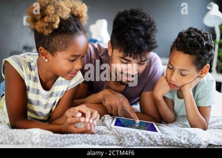 Happy family spending time at home and looking something fanny on tablet. Stock Photo