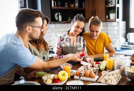 Group of happy friends having fun in kitchen, cooking food together Stock Photo